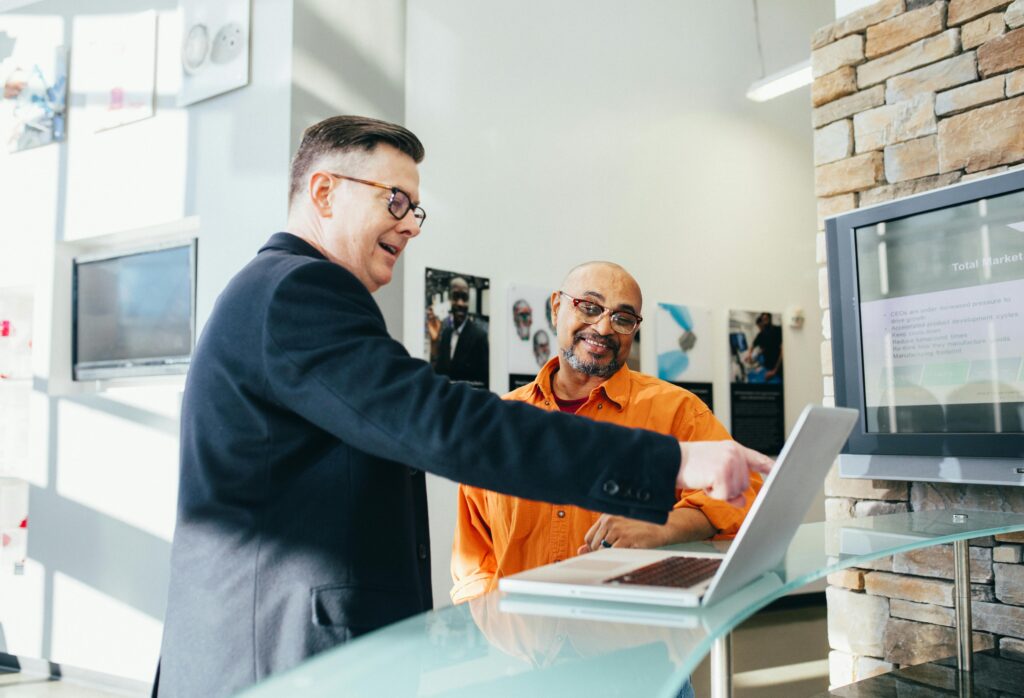 A man pointing at a laptop and smiling